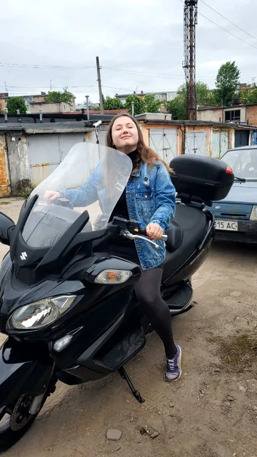 Настюня стоїть біля чорного максіскутера